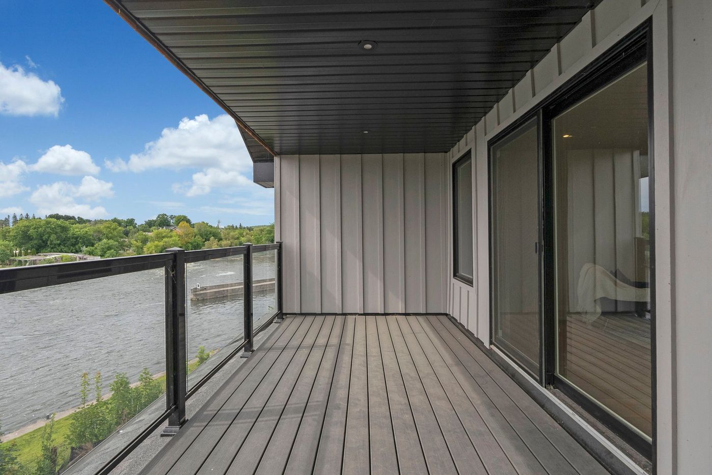 Covered balcony with glass railing and sliding doors